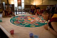 Tibetische Mönche streuen ein Sandmandala