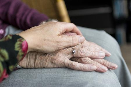Tochter hält die Hände ihrer alten Mutter