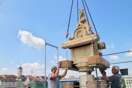 Mitarbeiter eines Spezialunternehmens aus dem Landkreis Regensburg brachten das „Bruckmandl“ in dieser Woche zurück auf seinen Platz auf dem Scheitelpunkt der Steinernen Brücke, die nach mehrjähriger Sanierung wiedereröffnet wird / Foto: obx-news/Jens Henning-Billon