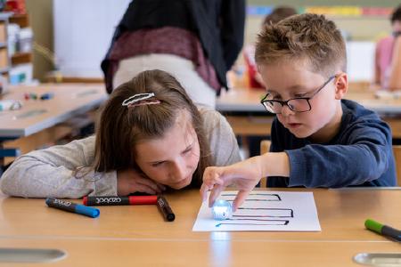 Informatik in der Grundschule: Die Kinder testen gemeinsam mit Prof. Dr. Gordon Fraser den Roboter auf ihrem Blatt Papier / Foto: obx-news/Universität Passau