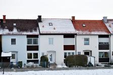 Sichtbarer Unterschied der Dämmung bei annähernd baugleichen Gebäuden: Während beim mittleren, gut gedämmten Haus der Schnee auf dem Dach liegen bleibt, ist die Schneedecke bei den beiden anderen Dächern abgetaut.