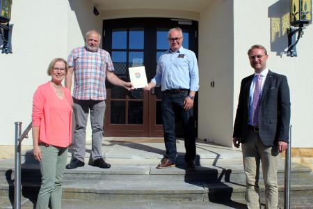 Erster Kreisbeigeordneter Dr. Jens Mischak (rechts) übergab gemeinsam mit Angelika Boese, Leiterin des Sachgebiets Dorf- und Regionalentwicklung des Vogelsbergkreises, einen Zuwendungsbescheid für den Neubau eines Funktionsgebäudes in Fraurombach an Willy Kreuzer (oben links), 1. Stadtrat der Stadt Schlitz, und Gerhard Marx, Ortsvorsteher von Fraurombach / Foto: Jennifer Sippel / Vogelsbergkreis