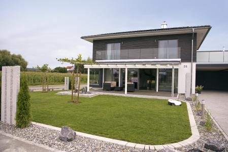 Das Muster Haus der Firma Fink Haus in Altshausen ist ein KfW-40-Plus-Effizienzhaus. Passend zur energetisch umweltfreundlichen und zukunftssicheren Philosophie mit eigener Stromerzeugung und der Nur-Strom-Haustechnik sorgt ein strombetriebener Rasenmäherroboter für das gepflegte Grün