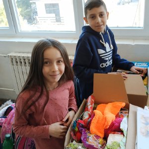 Kinder öffnen Päckchen der „Aktion Kinder helfen Kindern“