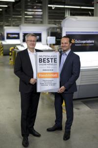 diedruckerei.de-CEO Dr. Michael Fries (l.) und CFO Dirk A. Müller halten das neue Siegel hoch: In der aktuellen Kundenumfrage von Handelsblatt und ServiceValue setzte sich diedruckerei.de gegen Mitbewerber durch und darf sich „Deutschlands bester Online-Händler“ nennen / Copyright: Onlineprinters GmbH