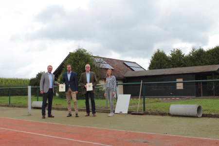 Einmal Schlitz, einmal Üllershausen: Im Rahmen der Dorfentwicklung werden zwei Projekte mit einer Zuwendung bedacht. Erster Kreisbeigeordneter Dr. Jens Mischak (links) übergibt am ehemaligen Gelände des Tennisvereins in Schlitz gemeinsam mit Jana Brittner (rechts), vom Amt für Wirtschaft und den ländlichen Raum, Sachgebiet Dorf- und Regionalentwicklung, die Zuwendungsbescheide an Stadtrat Heiko Siemon (CDU, Zweiter von links) und Martin Wedler, Leiter Fachbereich Technische Dienste der Stadt Schlitz. (Foto: Vogelsbergkreis/C.Lips)