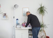 Ein Vater wickelt sein Kind in warmer Atmosphäre - dank dem neuen HeatCare+ Flex Wickeltisch-Wärmestrahler.