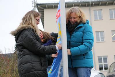 Sandra Obenhack (Koordinatorin im Familienbündnis), Stephanie Kötschau (Beauftragte für Integration, Inklusion und Gleichstellung) und Michaela Stefan (WIR-Koordinatorin) beim Hissen der Fahne (Foto: Gaby Richter)