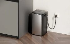 Kompakter, silberner EcoFlow STREAM AC Pro Energiespeicher steht auf Parkettboden neben einer Kücheninsel und ist mit einer Steckdose verbunden.