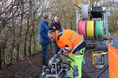 Gleich sieben Kabel werden am Stadtrand von Ulrichstein mit Druckluft in ein Leerrohr geblasen. Durch eine der bunten Röhren wird dann das Glasfaserkabel nach Feldkrücken führen, denn „Schritt für Schritt werden auch die kleinen Dörfer im Vogelsbergkreis mit schnellem Internet versorgt“, betont Landrat Manfred Görig beim Besuch auf der Baustelle / Foto: Sabine Galle-Schäfer/Vogelsbergkreis