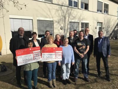 Landrat Michael Cyriax (2. Reihe, Dritter von rechts) und Markus Franz, Vorstandsmitglied der Taunus Sparkasse (2. Reihe, Zweiter von rechts) übergeben gemeinsam mit Susanne Schulmeyer, Filialleiterin Hattersheim (2. Reihe, Zweite von links) die Spendenschecks an die Einrichtungen EVIM Werkstatt Schlockerhof und die Kath. Kirchengemeinde St. Martinus