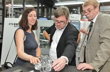 Dorothea Kliche-Behnke, Martin Rosemann und Harald Herrmann begutachten einen Stirlingmotor, den angehende Feinwerkmechaniker in der überbetrieblichen Ausbildung in Tübingen bauten (Foto: Handwerkskammer)