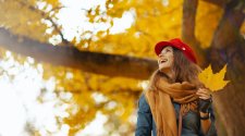 Frau steht unter Herbstbaum
