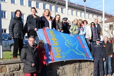 Das hat Tradition: Anlässlich des Gewaltschutztages wird vor dem Landratsamt die blaue Fahne der Menschenrechtsorganisation „terre des femmes“ gehisst - mit dabei unter anderem der Erste Kreisbeigeordnete Dr. Jens Mischak (untere Reihe, ganz links)und Gleichstellungsbeauftragte Stephanie Kötschau (obere Reihe, zweite von links). Foto: Sabine Galle-Schäfer/Vogelsbergkreis