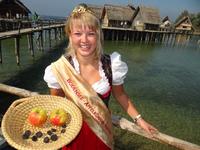 Die Bodensee Apfelkönigin Sonja Heimgartner – im Bild mit verkohlten Steinzeitäpfeln und der neuen Ernte - wird sich am 9.10. in den Pfahlbauten die Ehre geben. Copyright Pfahlbaumuseum Unteruhldingen
