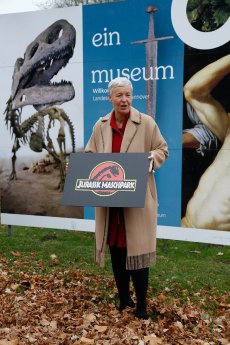 Katja Lembke (Direktorin) mit Jurassic Maschpark Schild (c) Landesmuseum Hannover.jpg