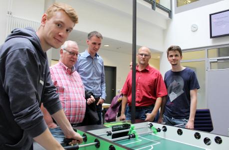 Philip Baumgartner, Viktor Koschmann und Lukas Völler zeigen Messebesuchern einen intelligenten Kickertisch, den sie verbessert haben. Damit ein Torwart automatisch gegnerische Schüsse automatisch abwehren kann, haben die Medieninformatik-Studenten die zugrundeliegende Software optimiert und neu strukturiert (Foto: Lidia Uffmann, Hochschule Osnabrück)