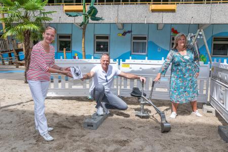 Ira Thorsting (li.), Vorsitzende Kleine Herzen Hannover, überreicht als Dankeschön ein Scherenschnittbild vom Vereinslogo an Marcus Berbic (Bildmitte), Geschäftsführer von mieterinfo.tv Kommunikationssysteme GmbH & Co. KG, für die wunderbare finanzielle Unterstützung bei der Anschaffung eines neuen Sandspielzeugbaggers für die MHH-Spieloase. Besonders freut sich auch Claudia Erzfeld Dokanikis (re.), Leiterin der Spieloase der Medizinischen Hochschule Hannover