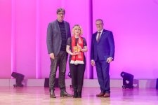 Laura Marie Bette bei der Abschlussfeier der „Deutschen Meisterschaft im Handwerk“ 2023 in Berlin. Ihren Preis als Bundessiegerin erhielt die Modistin aus den Händen von ZDH-Präsident Jörg Dittrich (rechts) und Bundestags-Mitglied Michael Kellner (links).