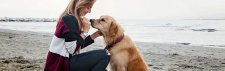 Frau und Golden Retriever am Strand
