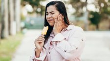 Frau isst Eis und reagiert empfindlich auf die Kälte