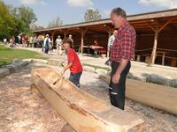 Im Steinzeitparcours der Pfahlbauten arbeiten Museumsbesucher an einem Einbaum. Einmaliger Abdruck frei, Copyright Pfahlbaumuseum  Unteruhldingen