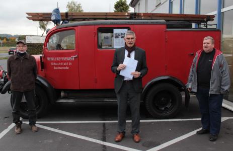 Ein nicht alltäglicher Autoverkauf: Landrat Manfred Görig übergibt Artur Schnitzer (rechts), dem Vorsitzender der Oldtimerfreunde Alsfeld, eine Spende in Höhe von 3000 Euro. Somit können die Alsfelder ein knapp 80 Jahre altes Feuerwehrauto zurückkaufen, das bislang Larry Gullickson (links) gehörte, der in der Schwalm eine kleine Sammlung historischer Fahrzeuge besitzt. Foto: Sabine Galle-Schäfer/Vogelsbergkreis