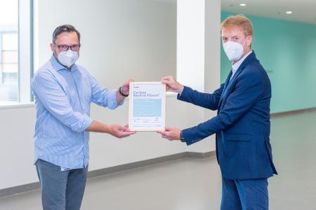 nora Marktsegment-Manager Klaus Link bescheinigt Stefan Binder, Leiter Planung und Bau, die Klimaneutralität der Bodenbeläge / Bild: Markus Kümmerle