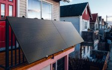 Das Bild zeigt ein modernes Balkonkraftwerk mit drei Solarmodulen an einem Balkon-Geländer in einer Wohnsiedlung – ein Beispiel für zeitgemäße, urbane Solarenergie im Alltag.