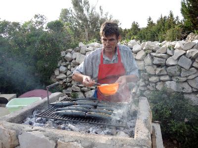 Pensionswirt Franz würzt die frischen Grillmakrelen.