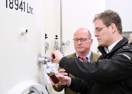 Braumeister Josef Erl (vorn) und sein Onkel Günter Erl prüfen den Reifegrad eines dunklen Biers, das in einem der rund 19.000 Liter fassenden Tanks lagert. Foto: obx-news/Jens Henning-Billon