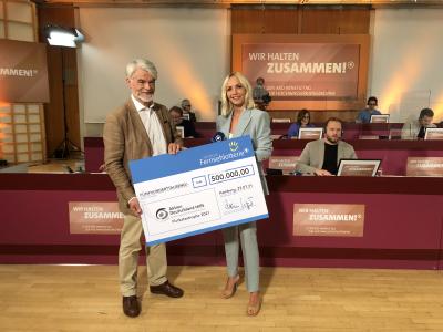Christian Kipper und Janin Ullmann präsentieren die Spende. Foto: Deutsche Fernsehlotterie / Daniel Kroll