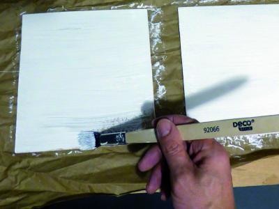 Dünne Holzplatten, weiß matt wie die Rahmen lackiert, ersetzen die eingeschobenen Plexiglasscheiben, damit Ständer für Werbeflyer angebracht werden können.