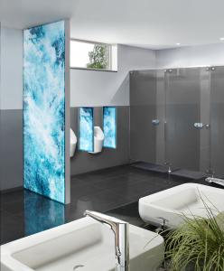 Die Urinaltrennwand mit LED verbindet Glas, Aluminium und beidseitige Lichteffekte zu kreativen Lösungen. Die grau bedruckten Glastrennwände des TWS 100 Plus passen perfekt dazu.
