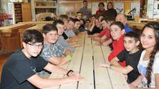 Die Schülerin und die 17 Schüler mit den Projektleitern und Ausbildern an den von ihnen angefertigten Sitzmöbeln.