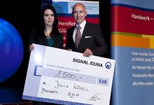 Als Jahresbeste wurde Fotografenmeisterin Julia Krall mit einer Auszeichnung durch Filialdirektor Jens Intelisano-Knollmann von der Signal-Iduna Versicherungen und Finanzen ausgezeichnet