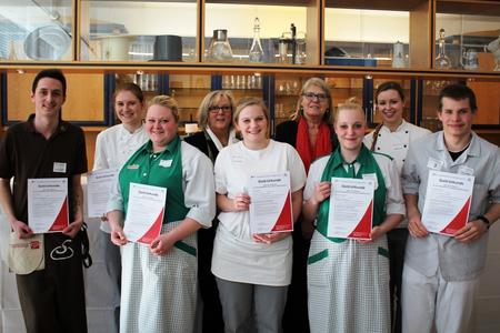 Schulleiterin Barbara Weichhold und Angelika Walther, stellvertretende Regionspräsidentin, gratulieren im Lehrrestaurant der BBS 2 den Siegerinnen und Siegern des diesjährigen Schulwettbewerbs (vorne, v.l.n.r.): Dennis Grandke, Miriam Eikenberg, Patricia Schmidt, Annika Weiß, Kim Bärbel Benedukt, Catharina Fey, Markus-Maik Langwost