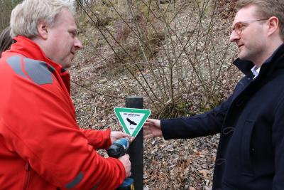 Thomas Gärtner (li.) und Dezernent Dr. Jens Mischak beim Aufstellen des Schildes: Es werden erstmals Pfosten aus recyceltem Kunststoff verwendet, die Naturdenkmalschilder enthalten zusätzlich das Vogelsberg-Logo und das Datum der Verordnung