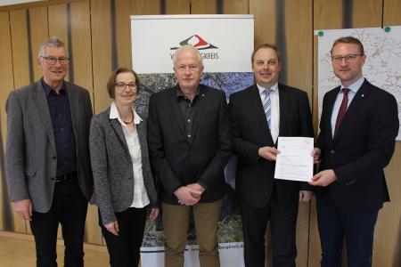 Erster Kreisbeigeordneter Dr. Jens Mischak überreicht Bürgermeister Alexander Altstadt im Beisein von Ortsvorsteher Holger Hohmeier, Angelika Boese (Amt für Wirtschaft und Ländlichen Raum, Dorf- und Regionalentwicklung) und Michael Poschen von der Vogelsberg Consult (von rechts) den Bewilligungsbescheid