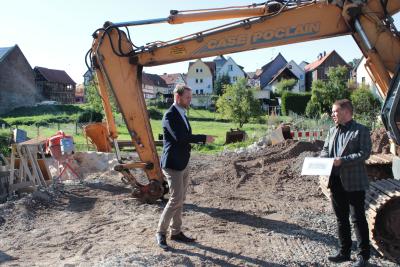 Erster Kreisbeigeordneter Dr. Jens Mischak (links, CDU) im Gespräch mit Karsten Jost, Geschäftsführer der Projektgesellschaft. Im Hintergrund soll das neue Medizinzentrum entstehen, das direkt an die sanierte Häuserzeile anschließt. (Foto: Christian Lips/Vogelsbergkreis)