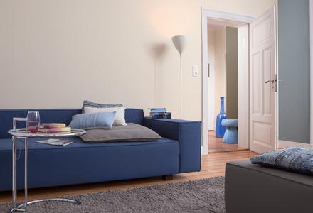 Das warme, helle Beige der Wände und ein ruhiges, kühles Blau als Ergänzung verleihen dem Raum eine erholsame Grundstimmung. Das blaue Sofa greift diese Schwingung auf und gibt – ganz entspannt – eine elegante Note dazu. Foto: Caparol Farben Lacke Bautenschutz