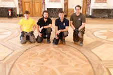 Hier fehlt nur noch der finale Schliff: Azubi Joris Sturm und die Parkettrestauratoren Eddy Keilbach, Marko Domschke und Lars Wildermann (von links) vor einem der schönen Ornamente im Parkett des Rittersaals. Foto: Handwerkskammer