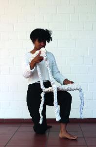 Raja Golz in einer Performance mit einem aus Bettlaken gehäkelten Stuhl aufgenommen von Katharina Paquet