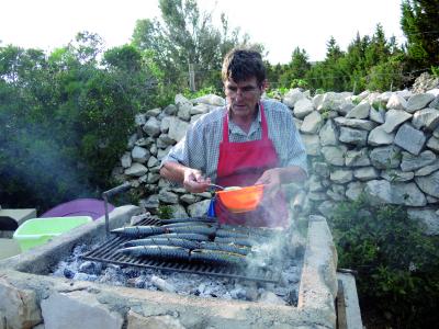 Pensionswirt Franz würzt die frischen Grillmakrelen.