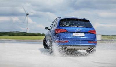 Heckansicht eines blauen Audi SQ5 bei Ausweichtraining auf nassem Skid-Pad.