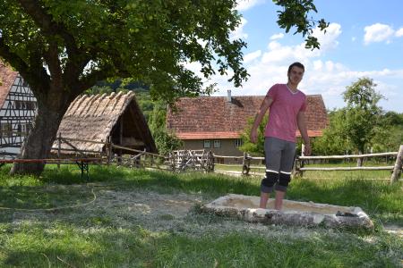 Lukas Düring auf dem neuen Sinnesparcours im Freilichtmuseum Beuren, der noch bis Ende September zu entdecken ist. Neun Felder sind mit unterschiedlichen Materialien befüllt – von Tannenzapfen bis Lehm / Foto: Freilichtmuseum Beuren