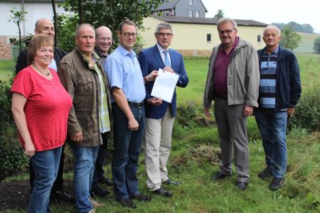 Der Ortsbeirat freut sich über die OVAG-Spende, die Landrat Manfred Görig für den geplanten Steg über die Berf überreichte: Der soll übrigens etwa dorthin, wo zwischen Landrat Görig und Ortsvorsteher Heinz Stumpf die Lücke klafft. (v. l.) Sigrun Wagner, Matthias Euler, Dietmar Ehrhardt, Marco Allendorf, Hans-Georg Ehrhardt-Gerst, Landrat Manfred Görig, Ortsvorsteher Heinz Stumpf und Erhard Berg, Foto: Gaby Richter