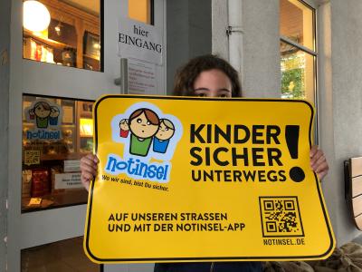 Kind mit Notinsel-Plakat
