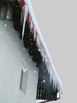 Eisbildung kann ein Hinweis auf verstopfte Fallrohre und nicht gereinigte Dachrinnen sein.