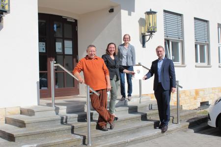 Der Erste Kreisbeigeordnete Dr. Jens Mischak (rechts, CDU) überreicht den Förderbescheid an Diana Dietrich (zweite von links), die die Pension „Grünes Paradies“ betreibt. Mitgesellschafter Armin Dietrich freut sich ebenso über die Förderzusage. Auch Angelika Boese vom Sachgebiet Dorf- und Regionalentwicklung vom Amt für Wirtschaft und den ländlichen Raum gratuliert zum gelungenen Projekt (Foto: Christian Lips/Vogelsbergkreis)